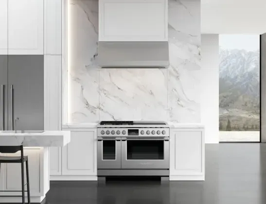 white vent hood with stainless steel stove and marble walls